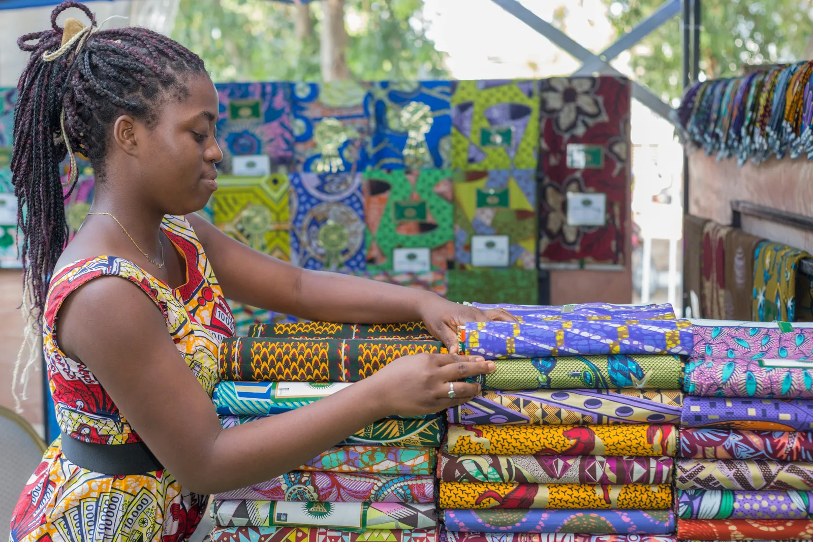 A Liberian business owner arranging wax-print textiles at her market stall